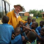 Terry Debay standing near van surrounded by curious and loving Kenyan children.