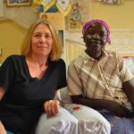 Lynn and Rebekah sitting inside next to each other with slight peaceful smiles.